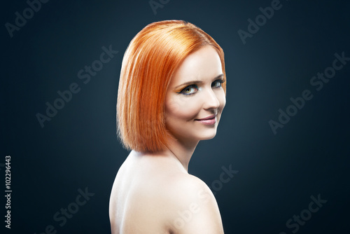 Beautiful young redhead woman isolated on dark background