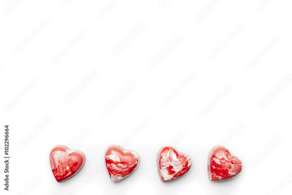 Red and white heart shaped chocolates arranged in line in the bottom on white background from above copy space Red and white heart shaped chocolates arranged in line in the bottom on white background from above copy space