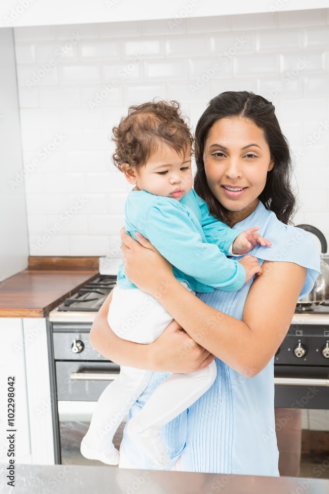Smiling brunette holding her baby and using laptop Smiling brunette holding her baby and using laptop
