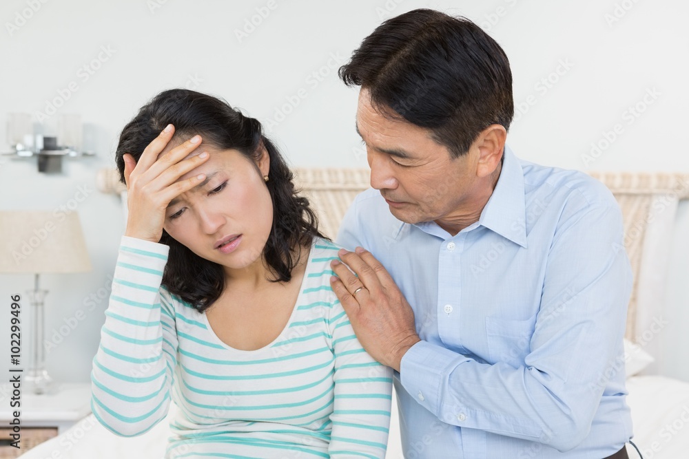 Woman with head ache sitting on bed Woman with head ache sitting on bed