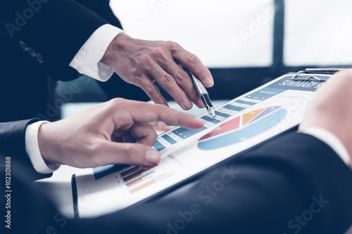 Two businessmen looking at report and having a discussion in off