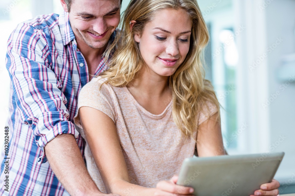 Cute couple using tablet computer in the kitchen Cute couple using tablet computer in the kitchen