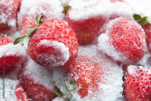 Obraz na płótnie Frozen strawberries with green leaves closeup