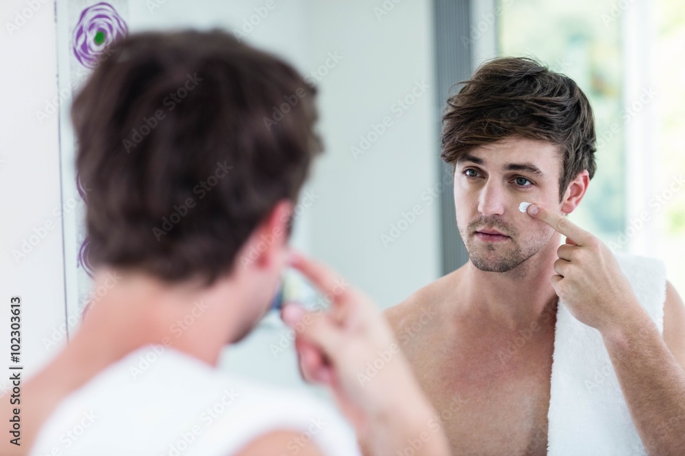 Smiling handsome man applying cream Smiling handsome man applying cream