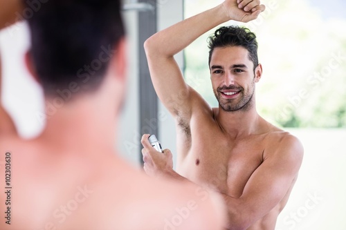 Handsome shirtless man putting deodorant photo