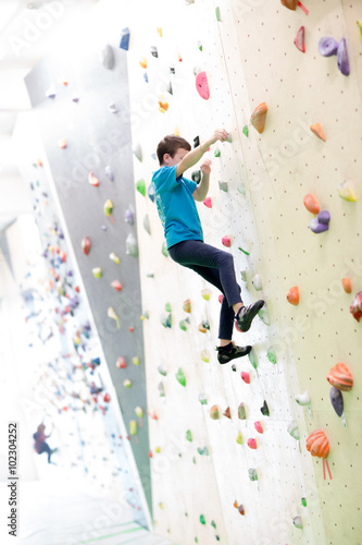 Bambino che scala una parete per arrampicata photo