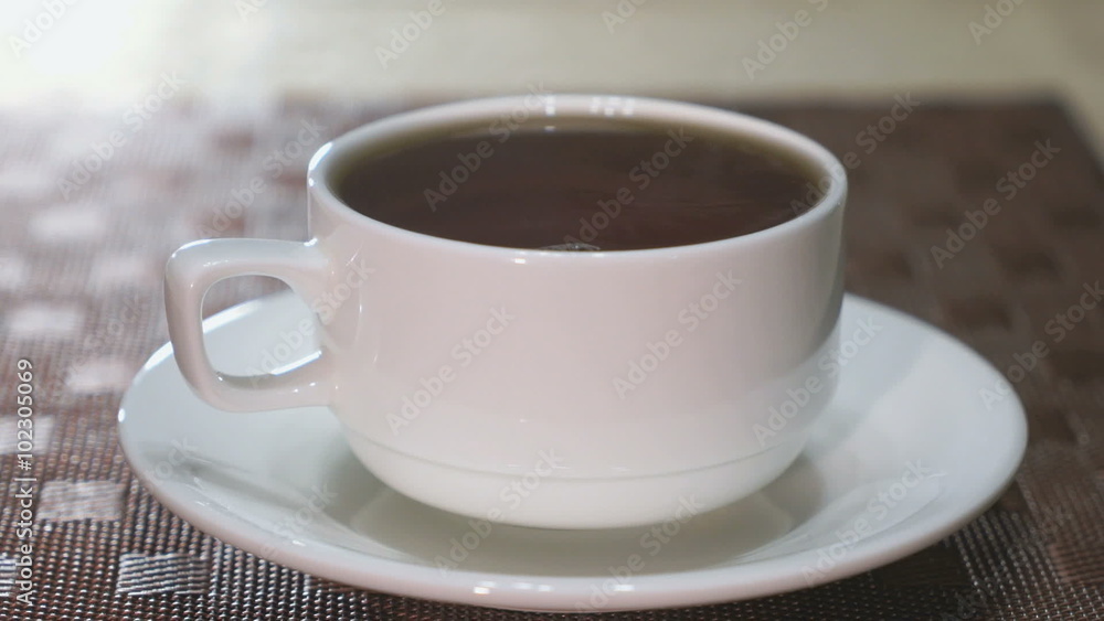 Porcelain mug with black tea is on the table. Steam coming from a mug Porcelain mug with black tea is on the table. Steam coming from a mug