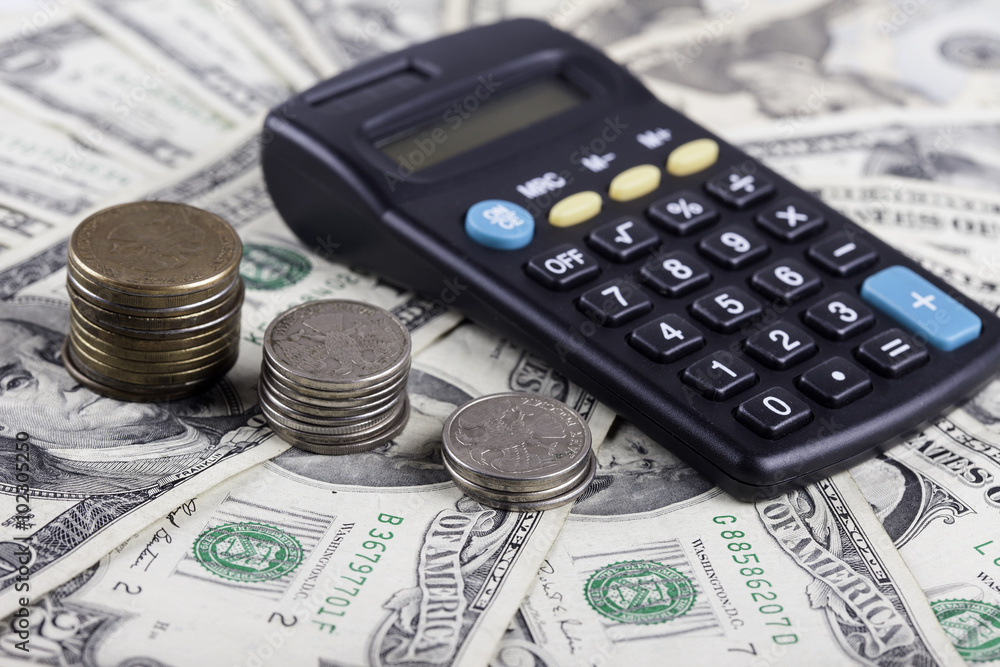 coins and calculator on the background of dollar banknotes coins and calculator on the background of dollar banknotes
