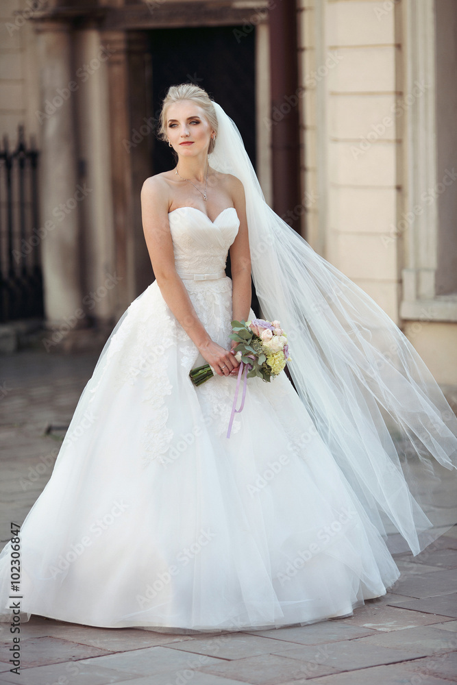 Beautiful fairytale blonde bride posing with bouquet in old ital Beautiful fairytale blonde bride posing with bouquet in old ital