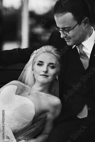 Beautiful blonde bride leaning against handsome happy goom on a