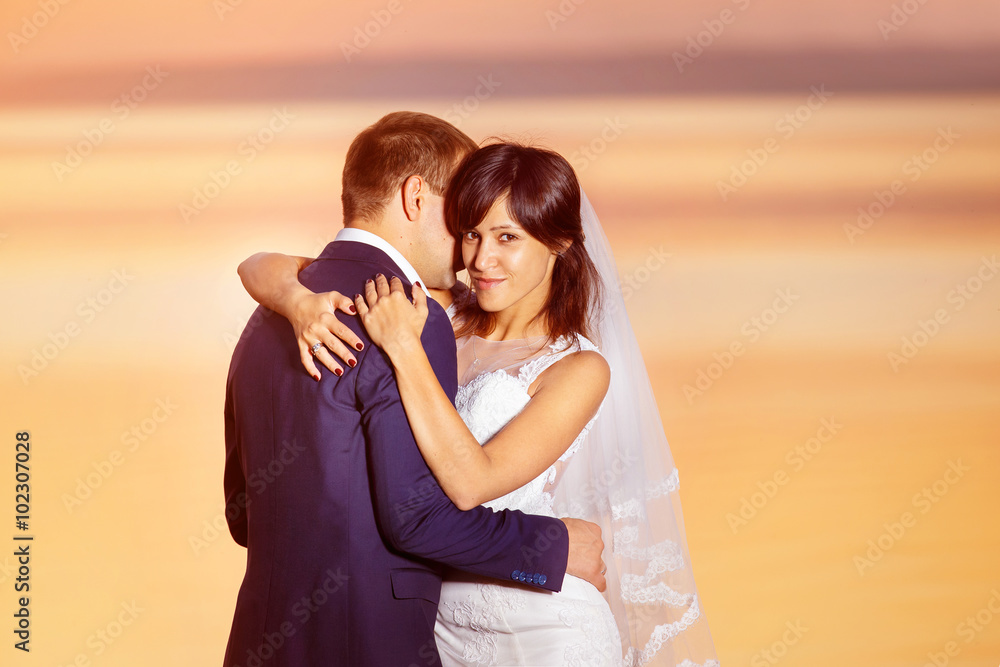 Beautiful couple is embracing at golden summer sea sunset Beautiful couple is embracing at golden summer sea sunset
