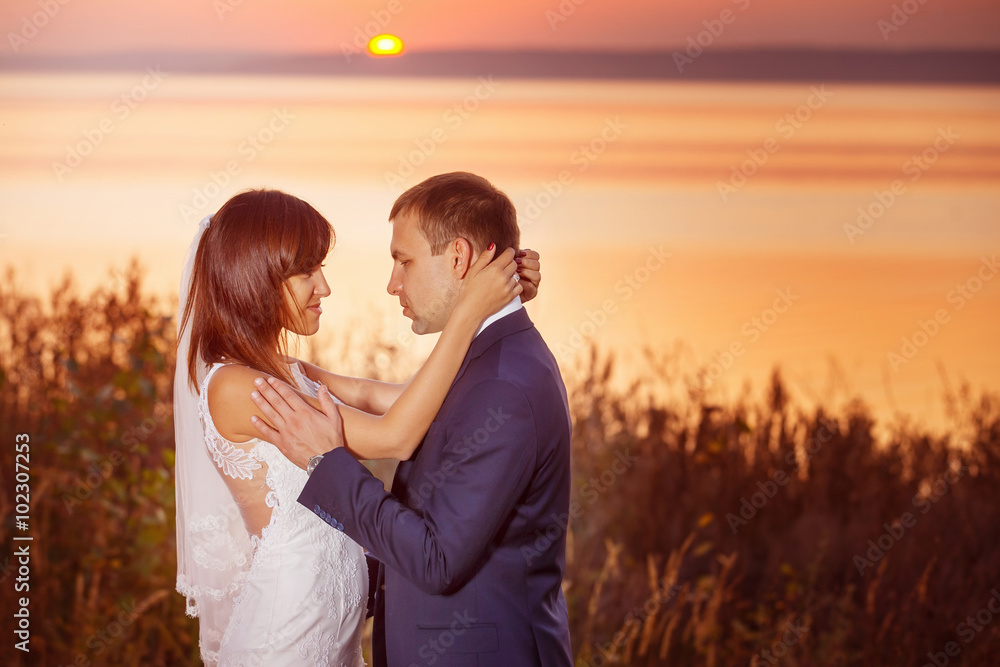 Beautiful happy couple is embracing at golden summer sea sunset Beautiful happy couple is embracing at golden summer sea sunset