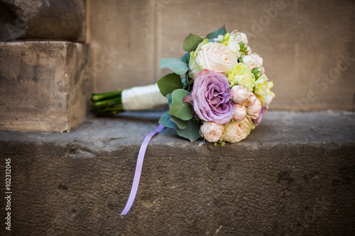 Romantic wedding bouquet, pink, purple and white roses on a ston photo