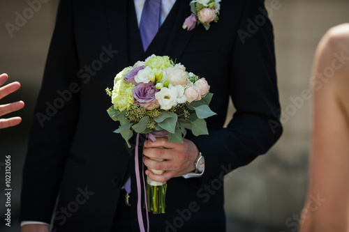 Handsome condifent groom holding beautiful wedding bouquet photo