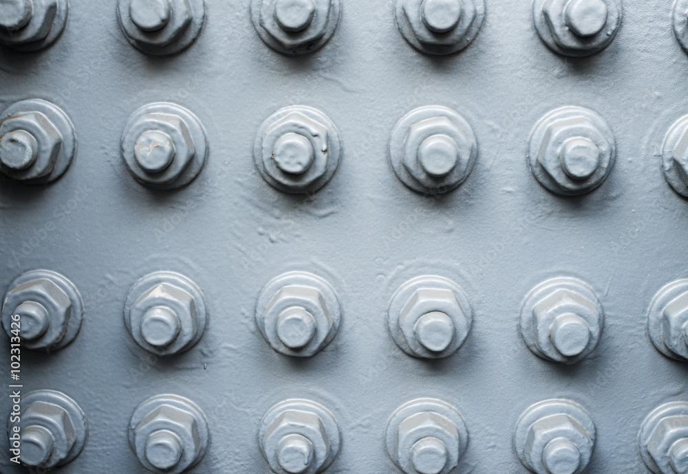 Gray painted metal surface with bolts and nuts Gray painted metal surface with bolts and nuts