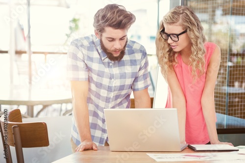 Composite image of a man using a laptop while discussing with a woman 