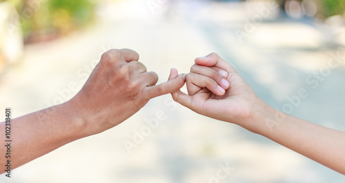 Parent and child hooking their fingers to make a promise photo