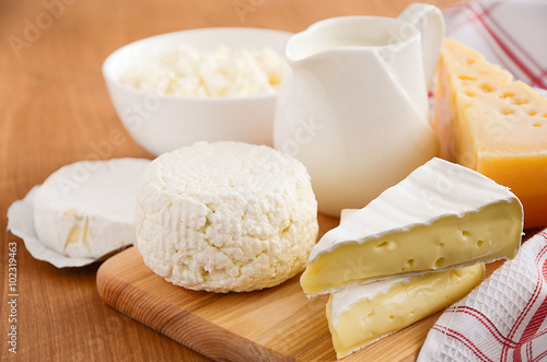 Fresh dairy products. Milk, cheese, brie, camembert and cottage cheese on the wooden background. Horizontal permission. Selective focus.