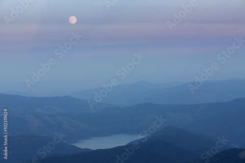 Full moon over mountains and lake