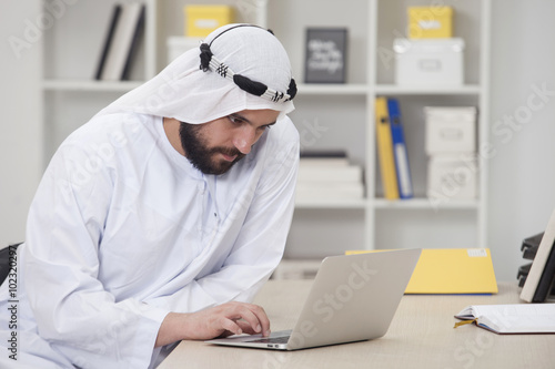 Young Arabic business man working on computer in his office photo