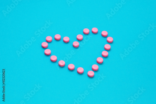 Pink Pills In Heart Shape on Blue background