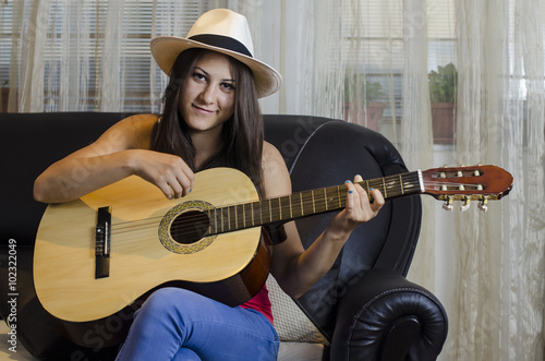 Young brunette with panama hat and guitar.