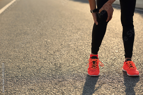  woman runner hold her injured leg on road.