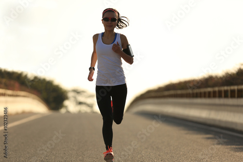 young sports woman runner running on city road