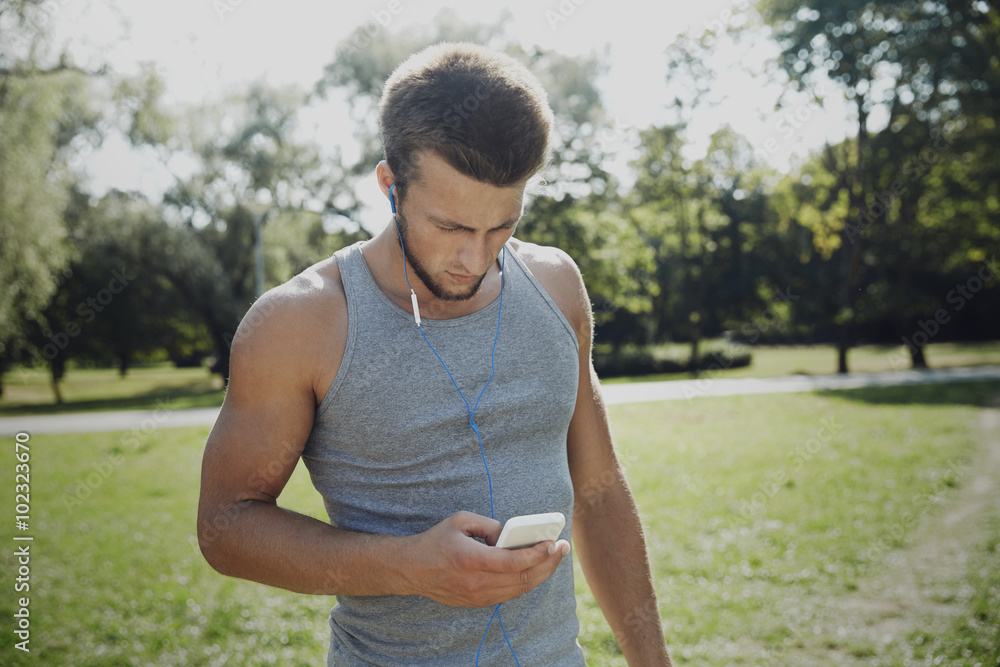 young man with earphones and smartphone at park young man with earphones and smartphone at park