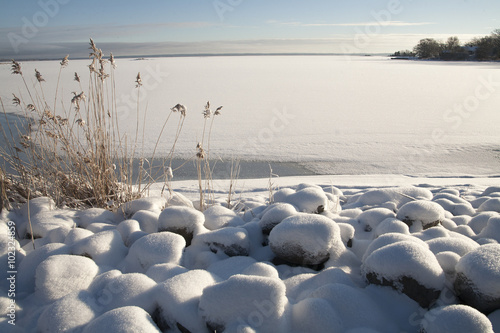 Kalmarsund,vik med utsikt mot Öland snöbelagd  stenar och vass i strandkanten photo