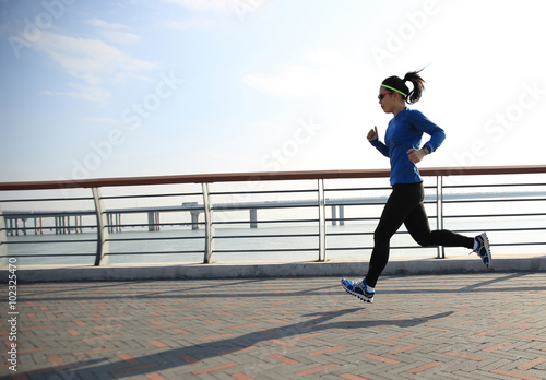 young fitness woman runner running on seaside road
