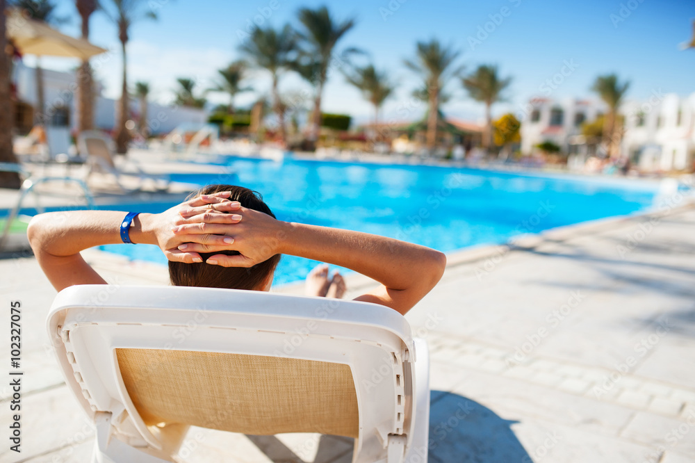 happy woman lying on a lounger by the pool at the hotel
