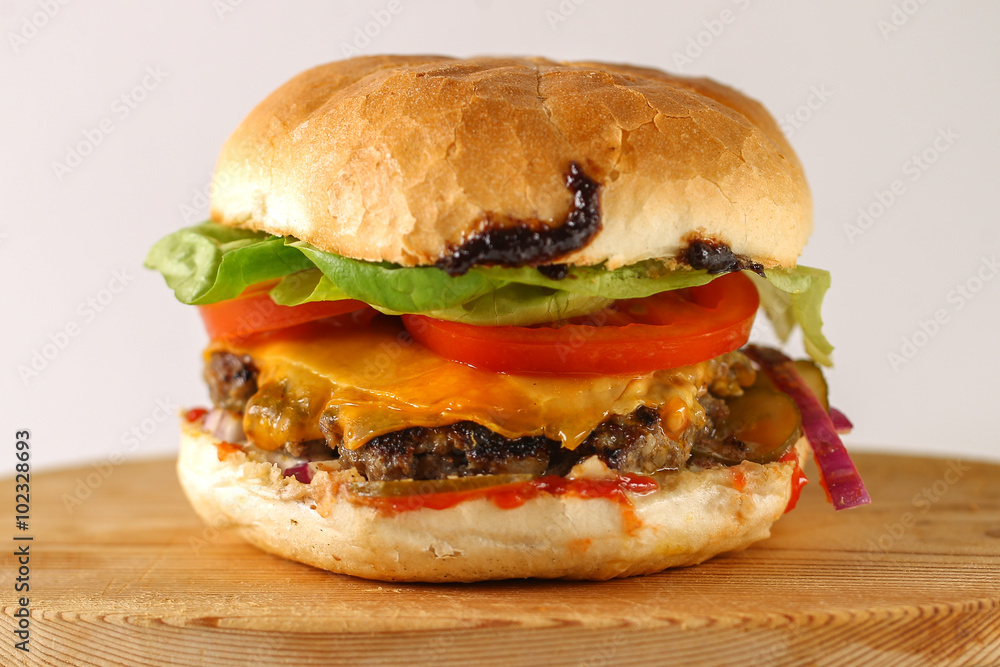 Tasty cheese beef burger with lettuce, cheddar, barbecue sauce, tomatoes, pickles and tzatziki