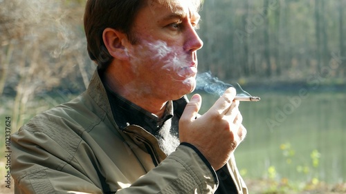 Tobacco smoker, caucasian man male smokes a cigarette, person in nicotine poison blue smoke