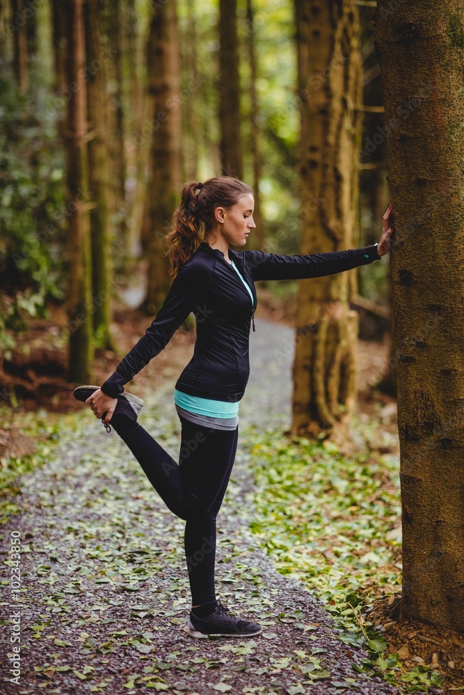 Fit brunette stretching against a tree Fit brunette stretching against a tree