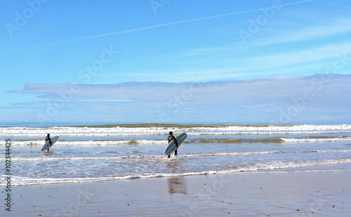 Sidi  Kaouki, Morocco -  January 7, 2016:  two surfers carrying a surfboard on the beach near Essaouira