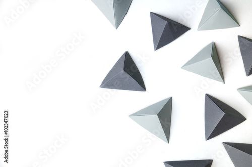 Creative background with black and gray origami tetrahedrons with free copy space on the left side. Great for using in web.