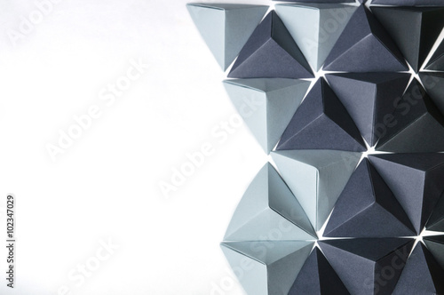 Creative background assembled with black and gray origami tetrahedrons with free copy space on the left side. Great for using in web.