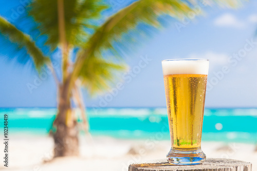 glass of cool beer on table near beach