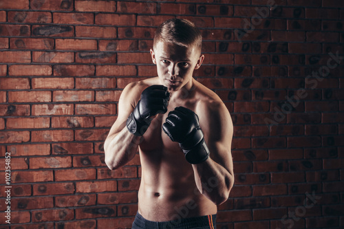portrait of mma fighter in boxing pose against brick wall