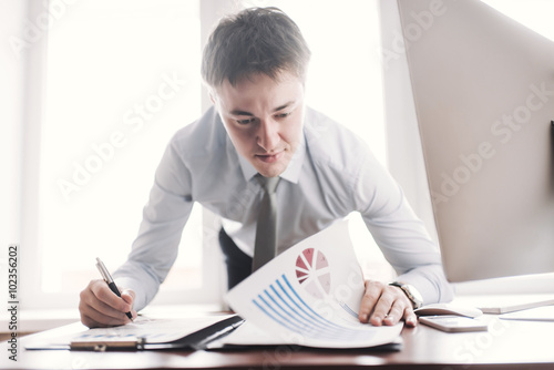 White business man signing a contract and looking at documents at his office while looking serious