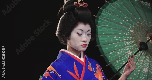 4K beautiful Japanese geisha dancing on stage and posing for the camera with an umbrella, in slow motion photo