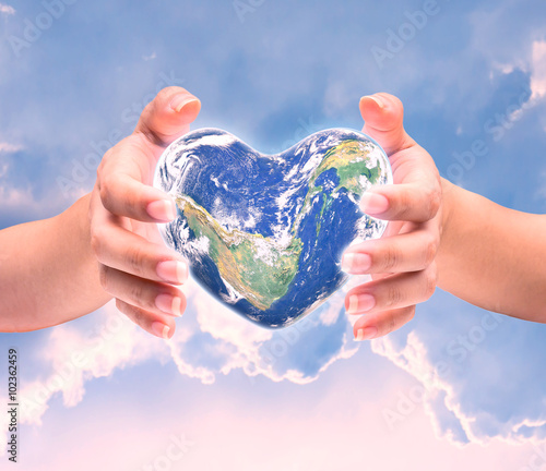 World in heart shape with over women human hands on blurred natu