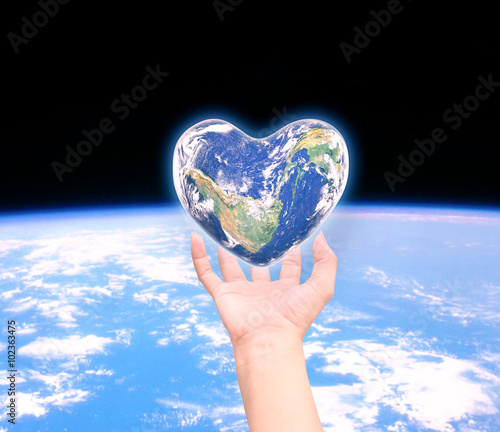 World in heart shape with over women human hands on blurred natu