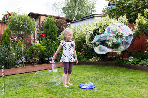 girl playing with soap bubbles in beautiful garden