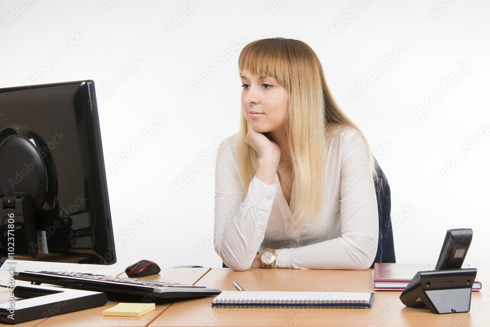 Business woman looking at a computer monitor at the table in the office Business woman looking at a computer monitor at the table in the office