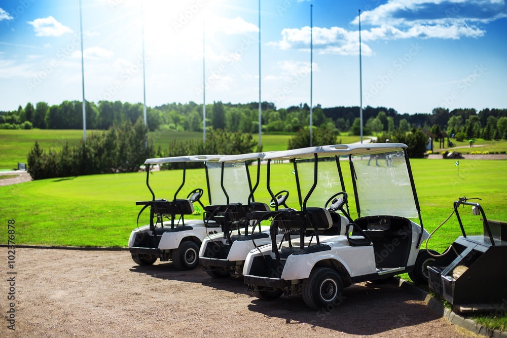 Club cars parking next to a golf course on a beautiful bright summer day