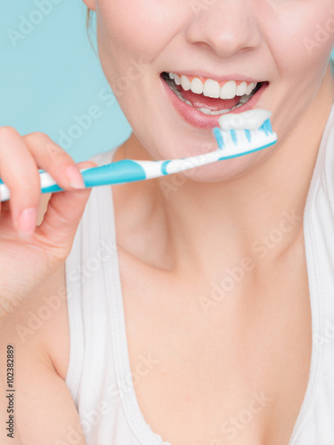 woman holds toothbrush with toothpaste cleaning teeth