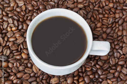 Cup of coffee surrounding by beans