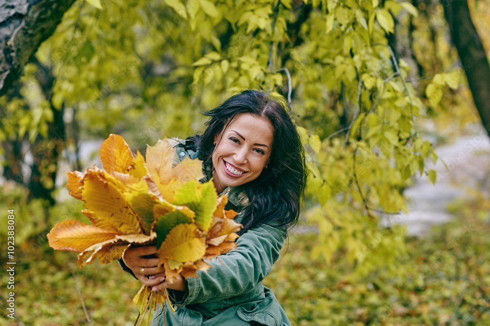 Smiling young attractive woman with autumn maple leaves in park at fall outdoors Smiling young attractive woman with autumn maple leaves in park at fall outdoors